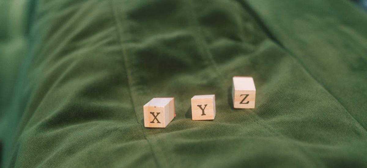 Wooden blocks with letters X, Y, Z on green fabric background.
