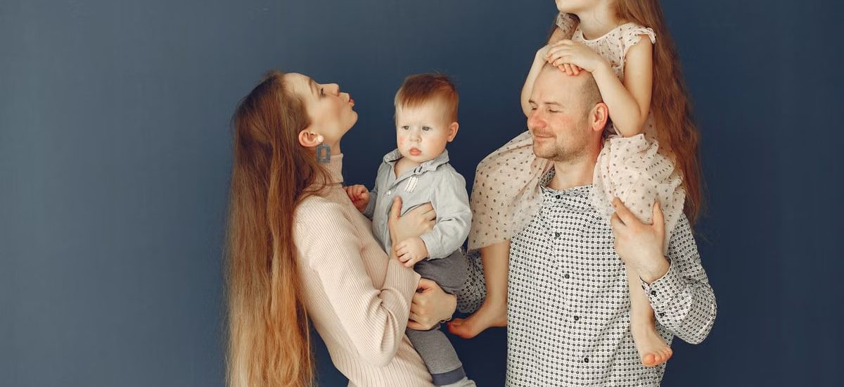 Portrait of a joyful family with parents and kids showing love and affection against a blue background.
