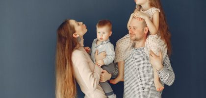 Portrait of a joyful family with parents and kids showing love and affection against a blue background.