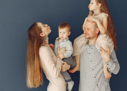 Portrait of a joyful family with parents and kids showing love and affection against a blue background.